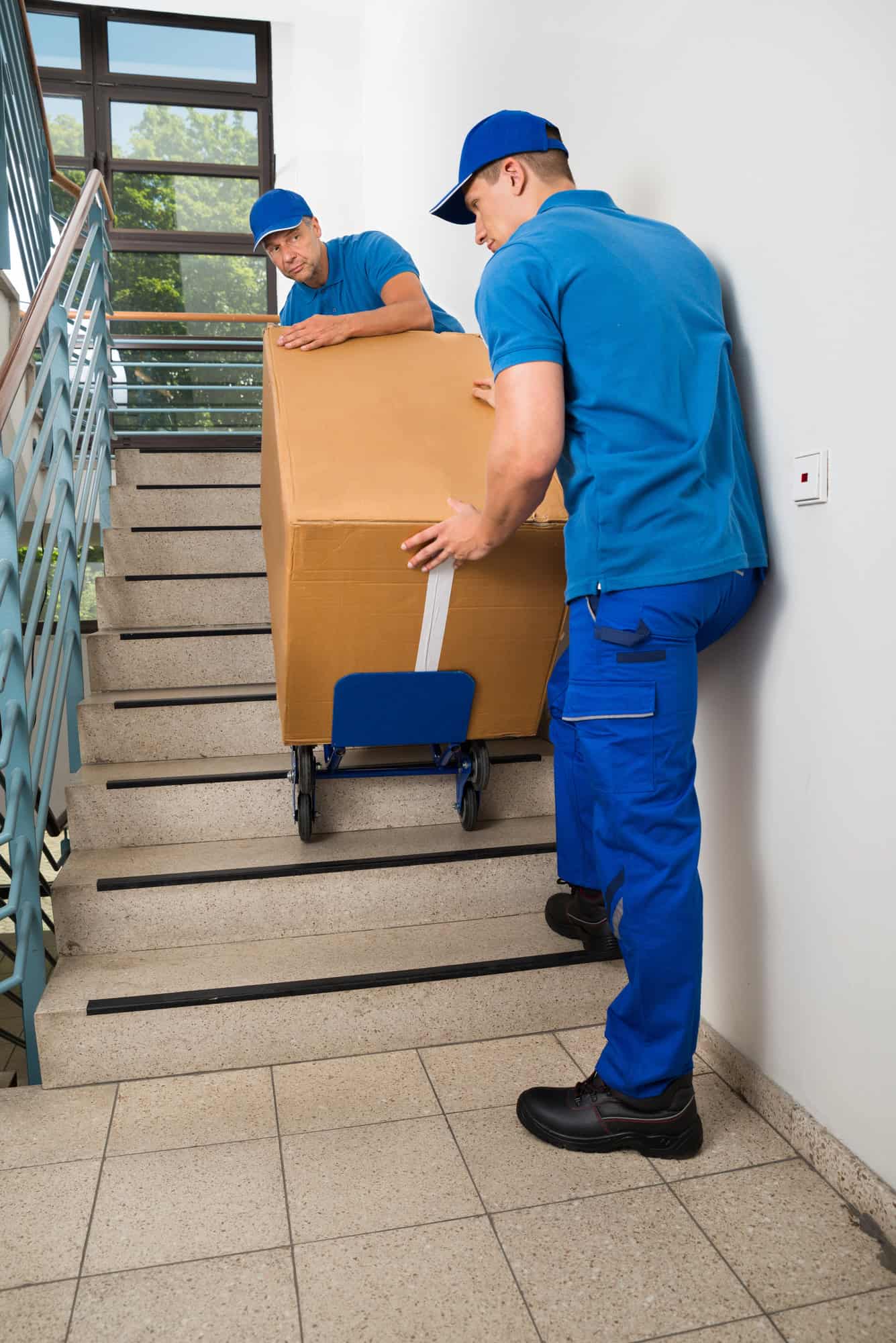 Two movers carrying a box down a staircase